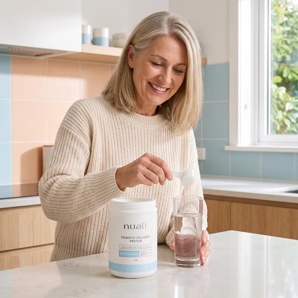 Woman in her fifties scooping Nualï collagen into a glass of water